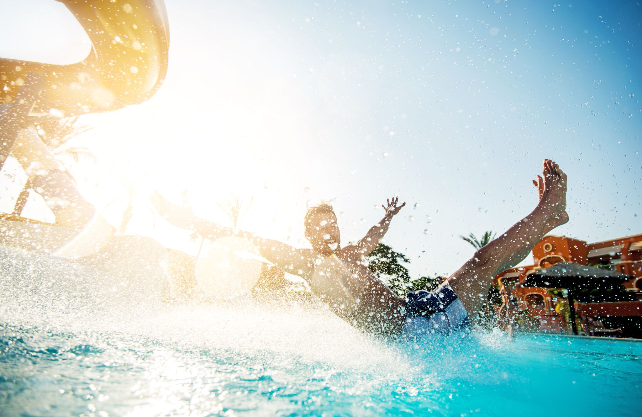 A child splashes joyfully in water at Lago Taurito Waterpark, with sunlight and palm trees creating a fun atmosphere.
