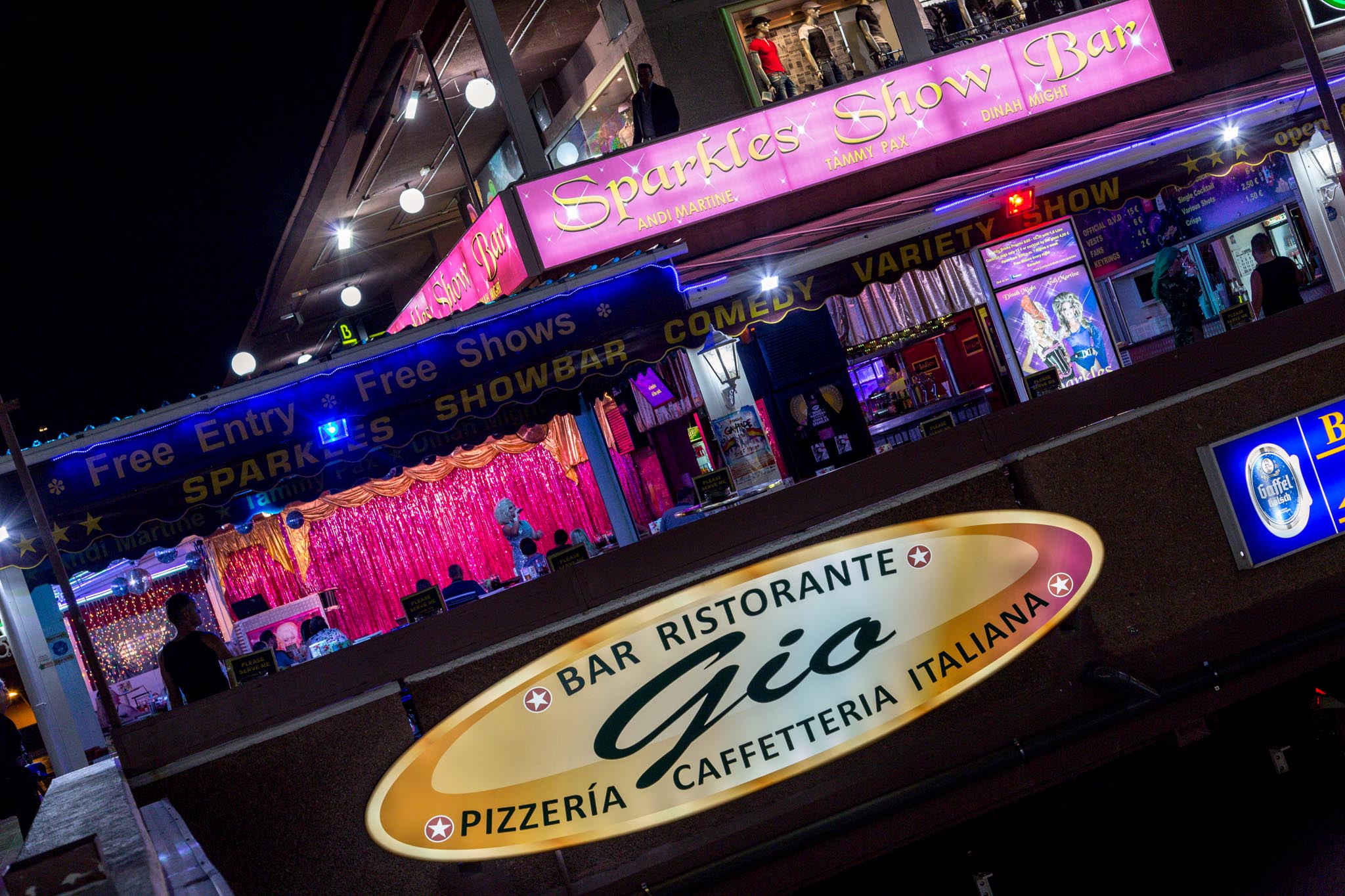 Brightly lit Yumbo Centre at night featuring a colorful show bar with a sparkling backdrop and signs for free entry.