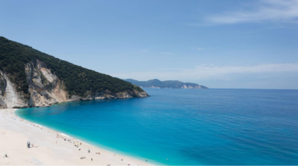 A beach with blue water and hills AI-generated content may be incorrect.