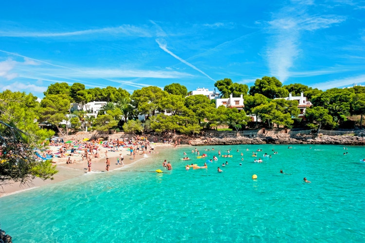Cal d'Or beach scene featuring swimmers enjoying the water and sunbathers relaxing on the sandy shore.
