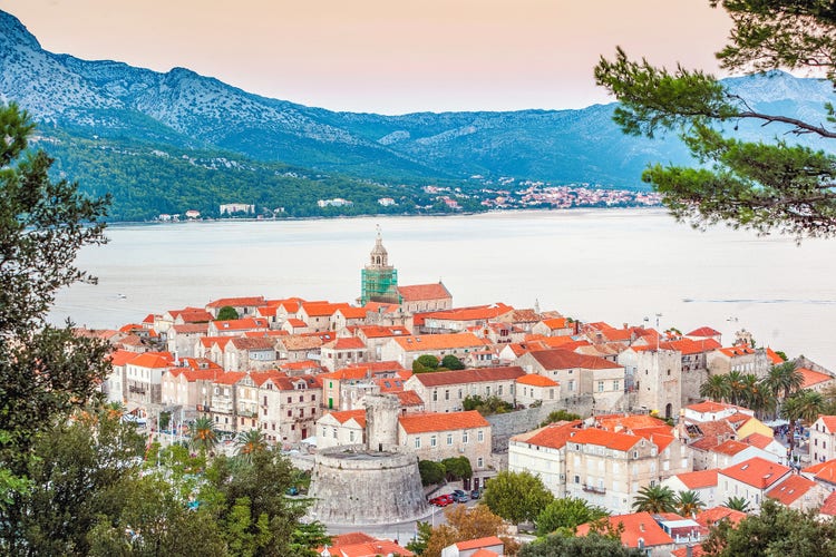 Panoramic view of Korčula Island featuring historic buildings with red rooftops, set against a serene coastal backdrop.