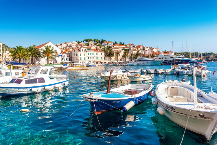 Vibrant marina at Hvar Island featuring boats, palm trees, and colorful buildings along the waterfront.