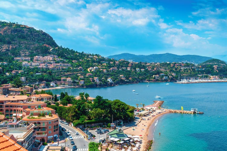 Panoramic view of Théoule Sur Mer, showcasing lush hills, colorful homes, and a serene blue coastline with boats.