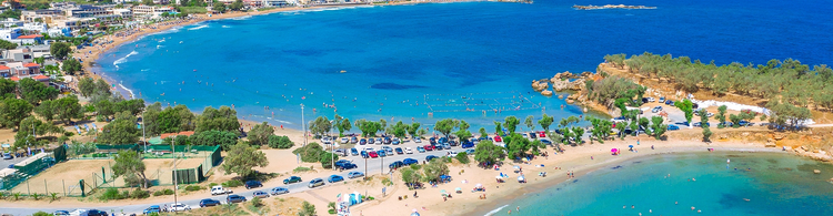 A Greek salad with peppers, olives, and bread, accompanied by a glass of wine, set against a seaside background in Kato Daratso.
