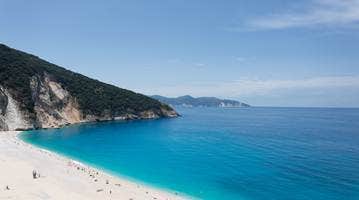 A beach with blue water and hills AI-generated content may be incorrect.