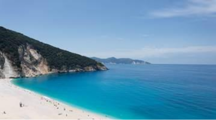 A beach with blue water and hills AI-generated content may be incorrect.