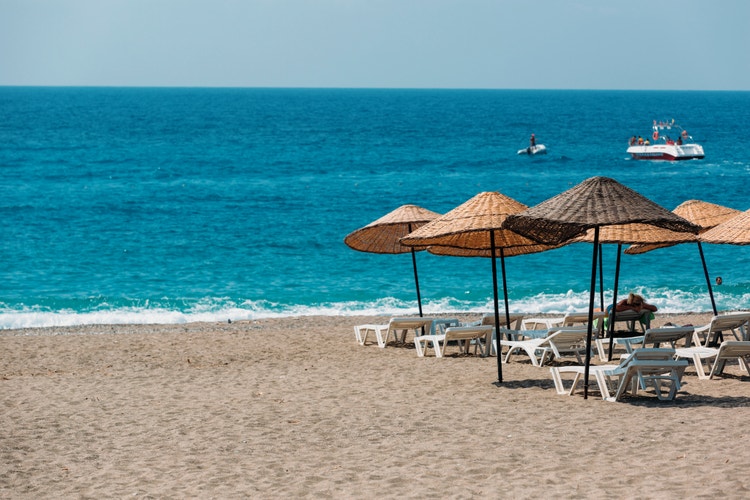 Beach umbrellas on a sunny Kargicak shore with gentle waves and a peaceful atmosphere. Relaxed beachgoers enjoy the view.