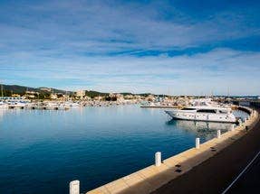 Calm marina scene with yachts docked along a curved pier in Roda de Bara on Spain’s Costa Dorada